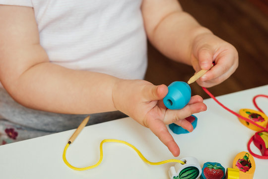 Toddler hands using beads and a lace