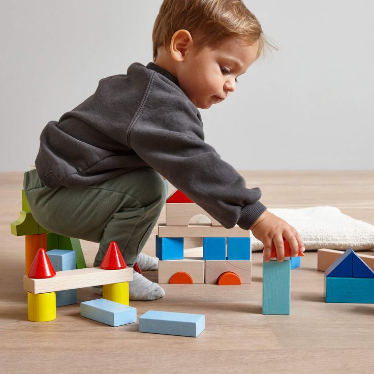 Toddler engaged in quiet independent play with wooden building blocks in a serene nursery corner